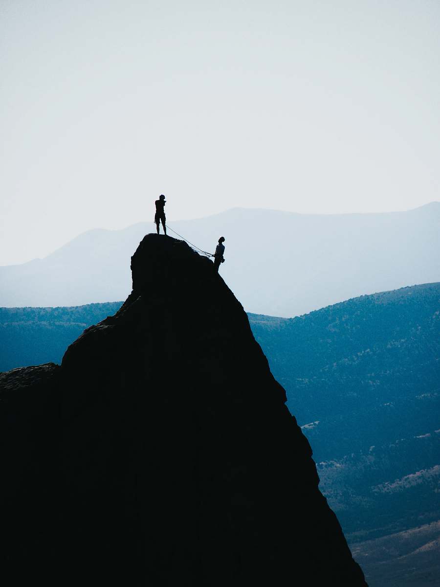 adventure silhouette of two people standing on mountain during daytime outdoors